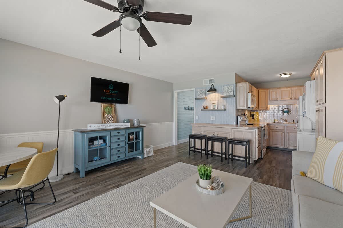 The Summit 919 – Living room and kitchen area with modern furnishings, dining table, and ceiling fan.