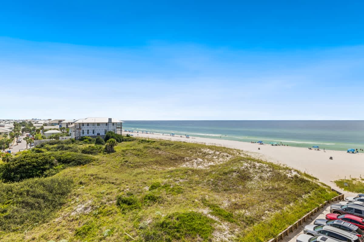 Pinnacle Port 304A – View of a beach, ocean, and nearby buildings from a vacation rental balcony.