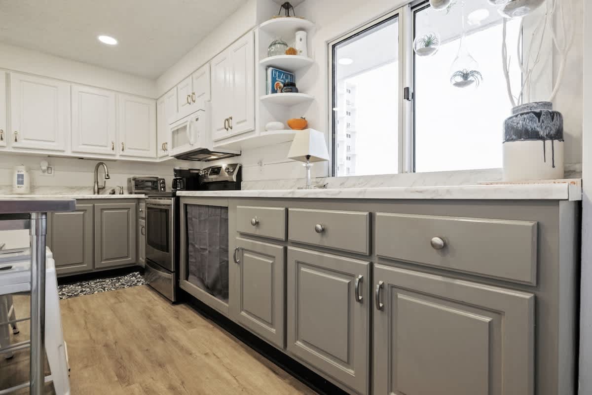 Pinnacle Port 304A – Bright kitchen with white and gray cabinets, stainless steel appliances, and a view through large windows.