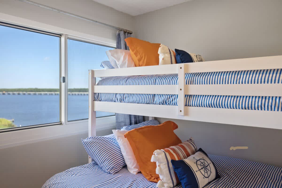 Pinnacle Port 304A – Bunk beds with striped bedding and decorative pillows, window view of the water and bridge.