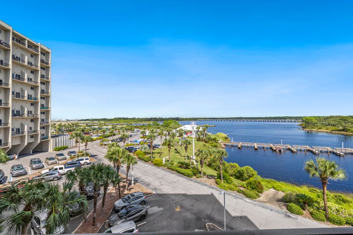 Pinnacle Port 304A – View of a parking lot, palm trees, and a serene body of water with docks and a bridge in the distance.