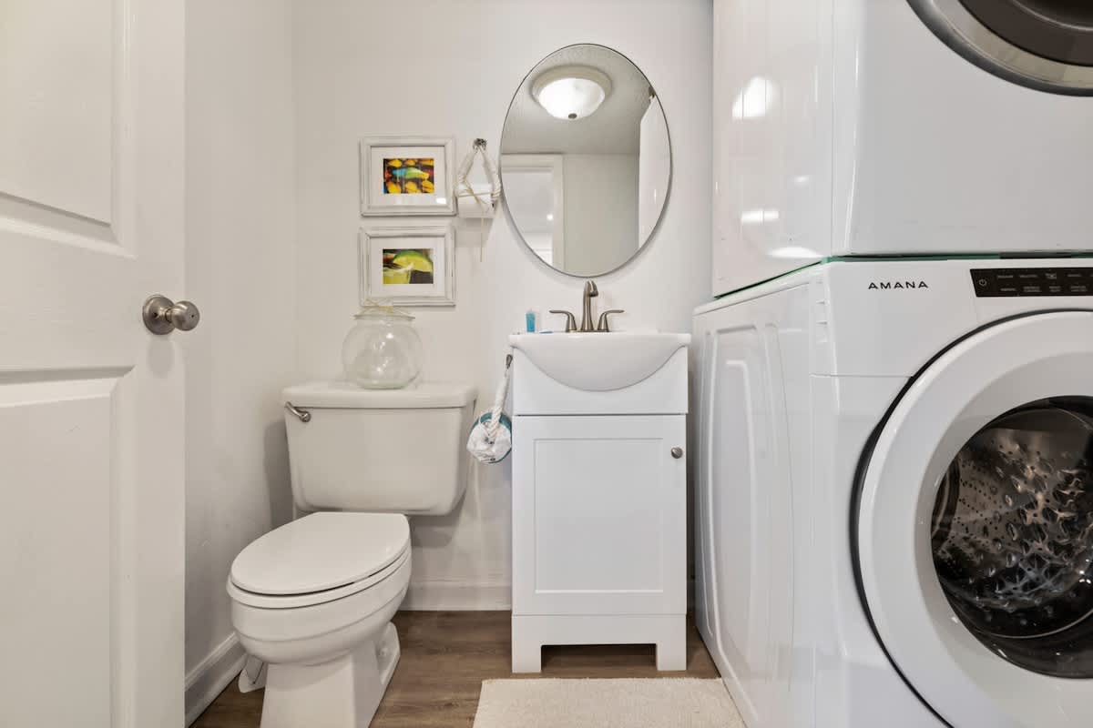 Pinnacle Port 304A – Compact laundry space featuring a toilet, sink, mirror, and stacked washer and dryer.
