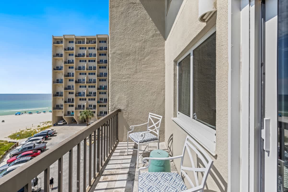 Pinnacle Port 304A – Balcony view with two chairs, turquoise table, and ocean in the background.