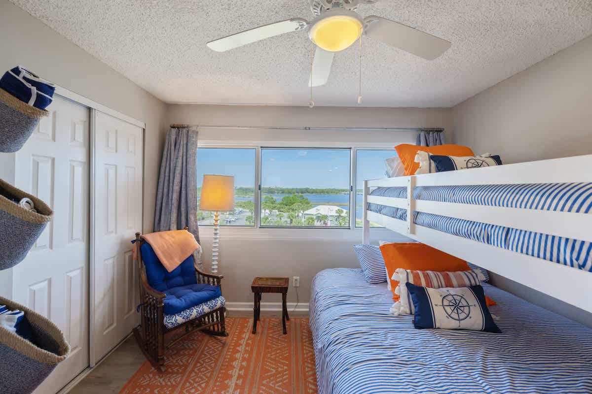 Pinnacle Port 304A – Bunk bedroom with a view, featuring a blue chair, lamp, and decorative pillows.
