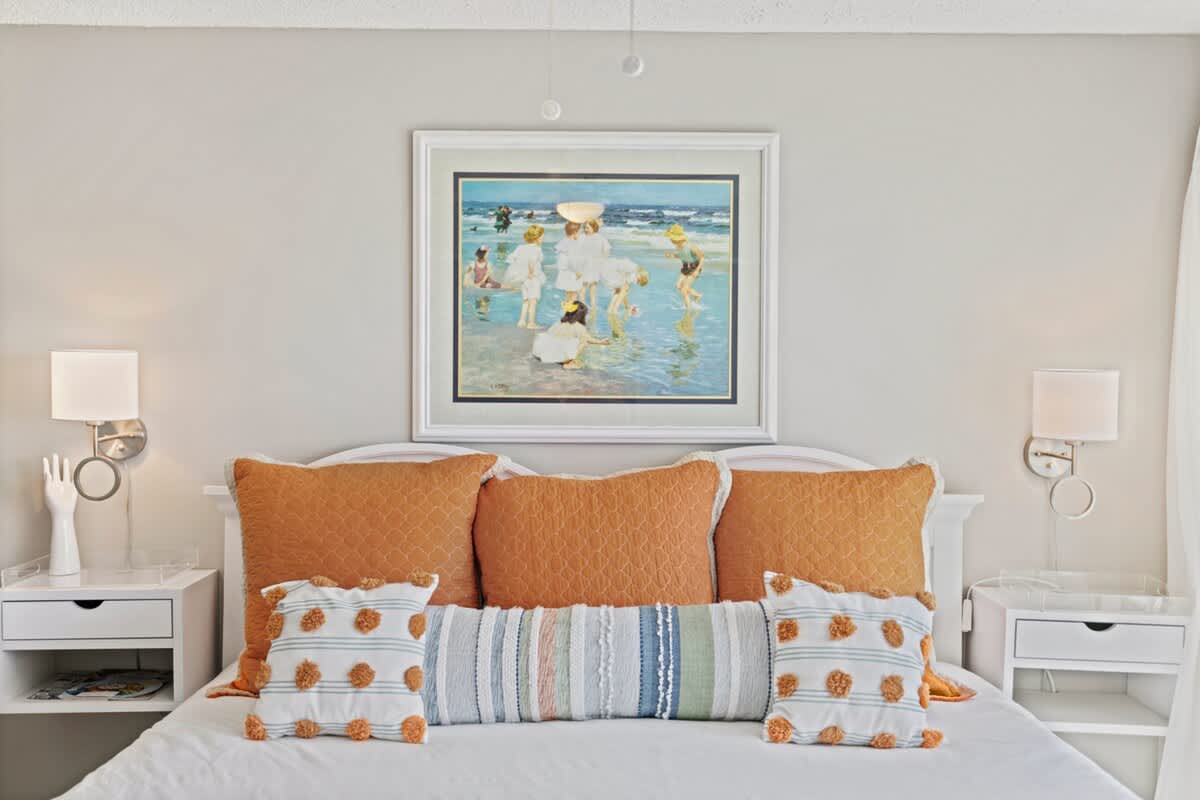 Pinnacle Port 304A – Bright bedroom with a large artwork, orange pillows, and bedside tables with lamps.