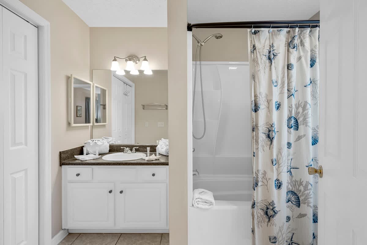126 Seagrass Way – Bathroom with double vanity, mirror, shower/tub combo, and decorative shower curtain.
