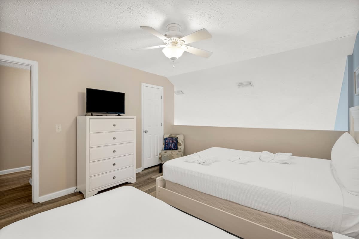 126 Seagrass Way – Cozy bedroom with two beds, dresser, TV, and small seating area