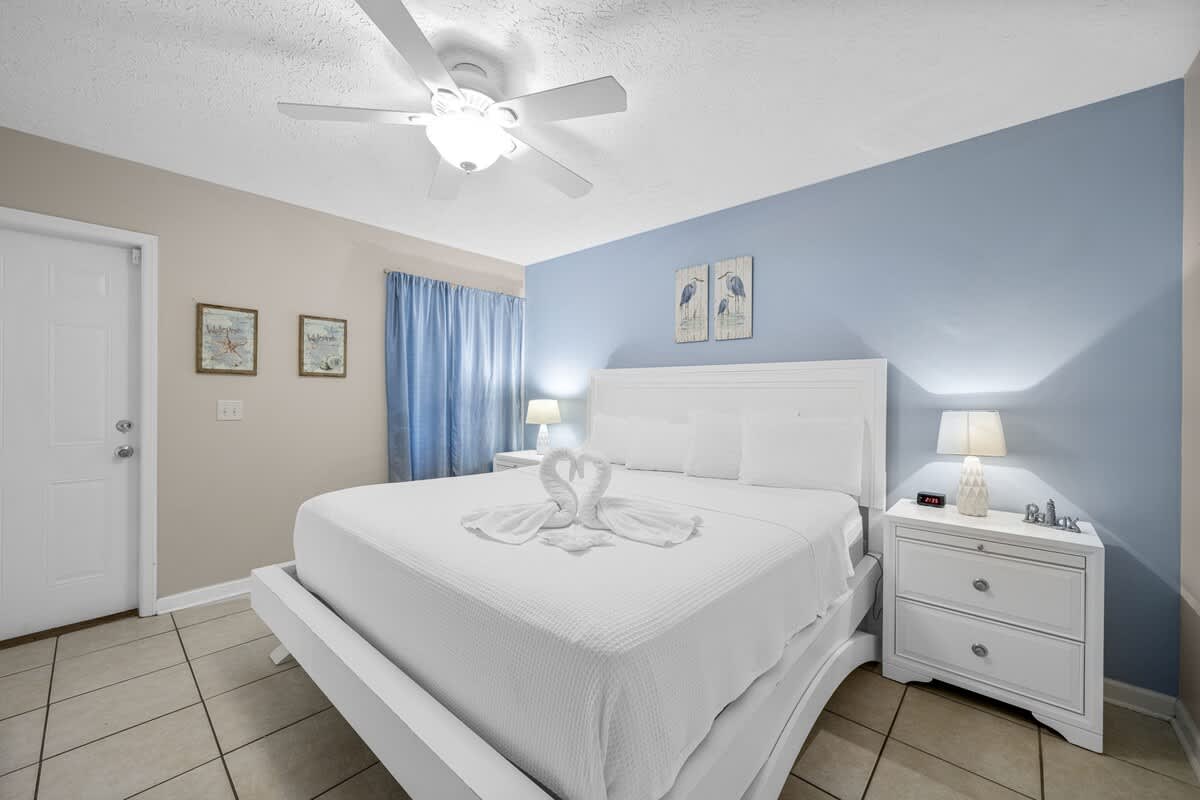 126 Seagrass Way – Bedroom with a white bed, blue wall, decorative artwork, and a lamp beside a nightstand.