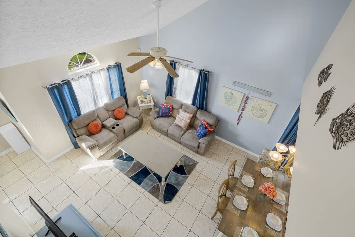 126 Seagrass Way – Living room with beige sofas, dining table, and decorative wall art. Bright natural light from windows.