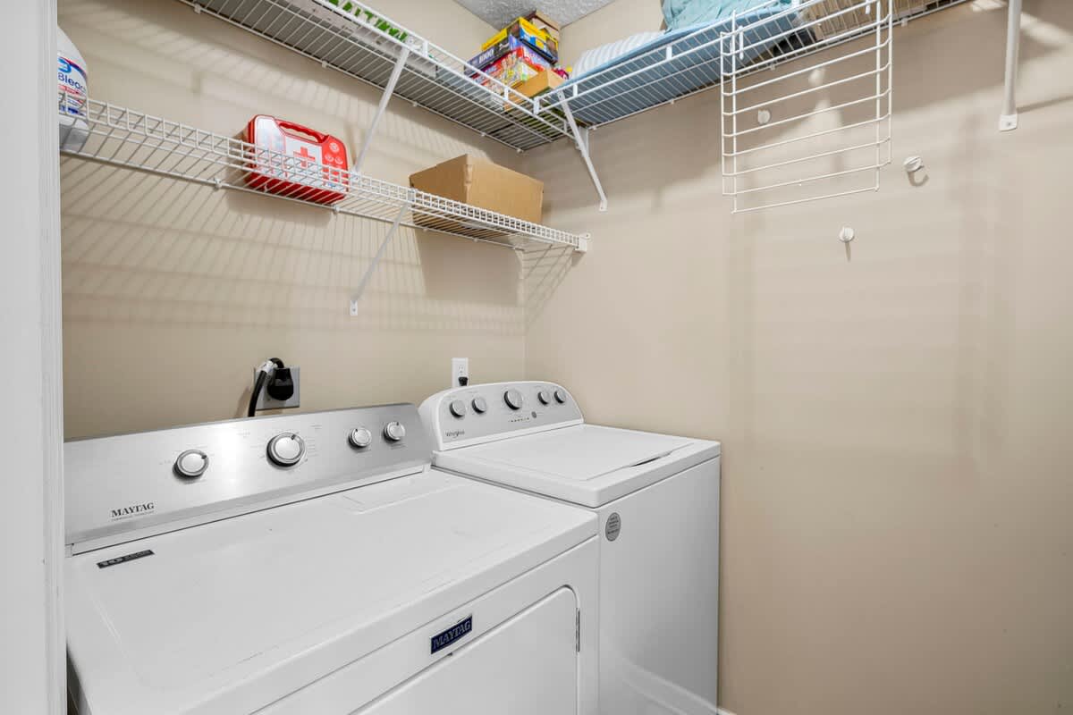 126 Seagrass Way – Laundry room featuring a washer and dryer with shelving above.