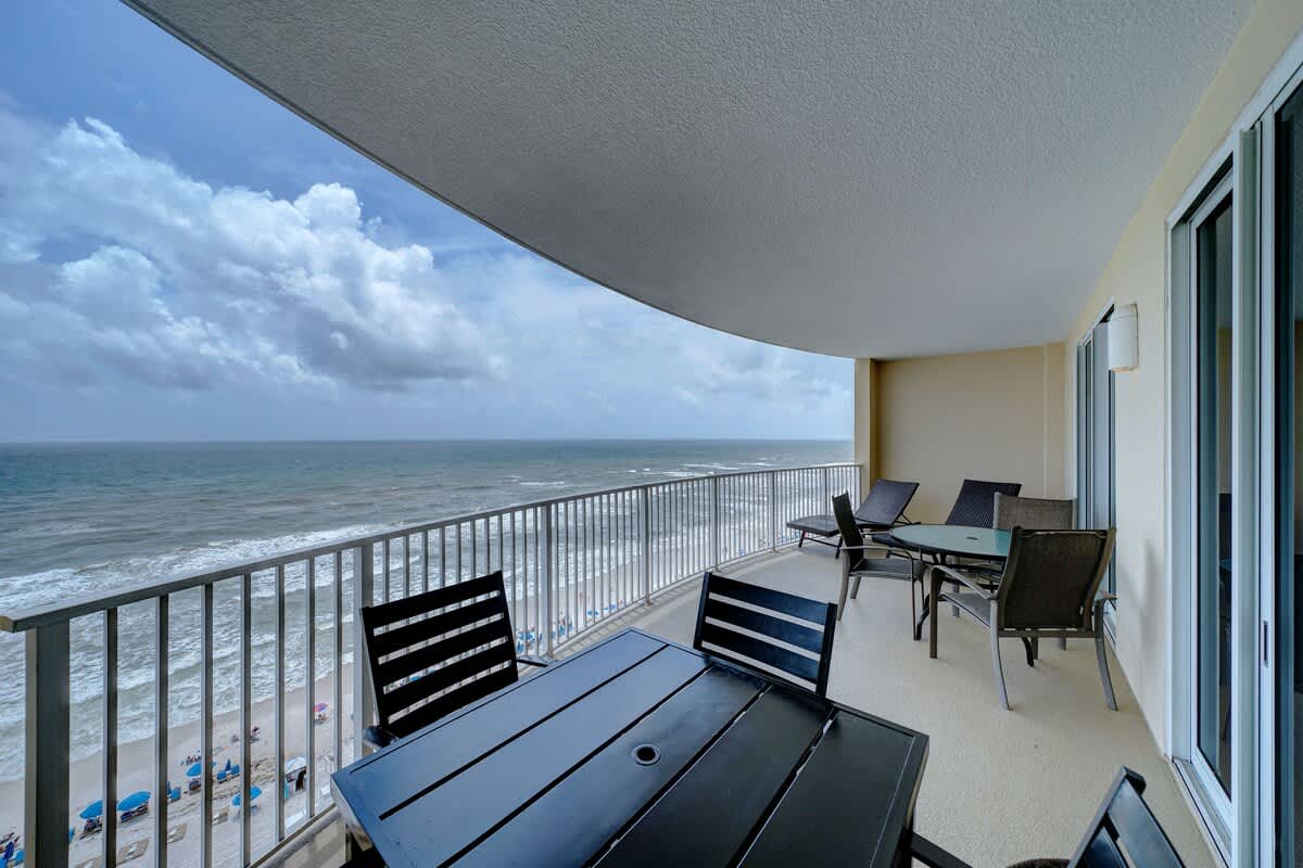 Ocean Villa 1104 – Balcony view of ocean with outdoor seating and tables overlooking the beach.