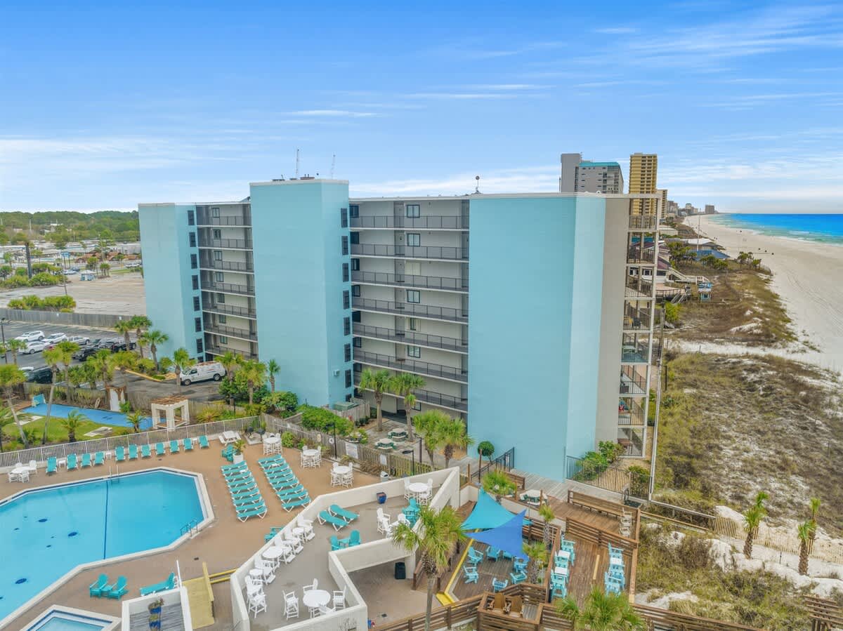 Moondrifter 207 – Pool area with lounge chairs and palm trees, view of the beach and ocean in the background.