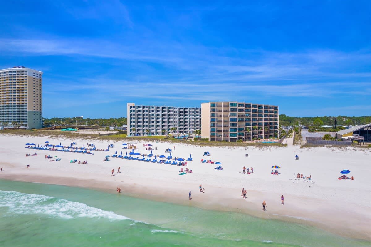 Moondrifter 207 – Aerial view of beach with umbrellas, Moondrifter 207 building, and surrounding beachfront properties.