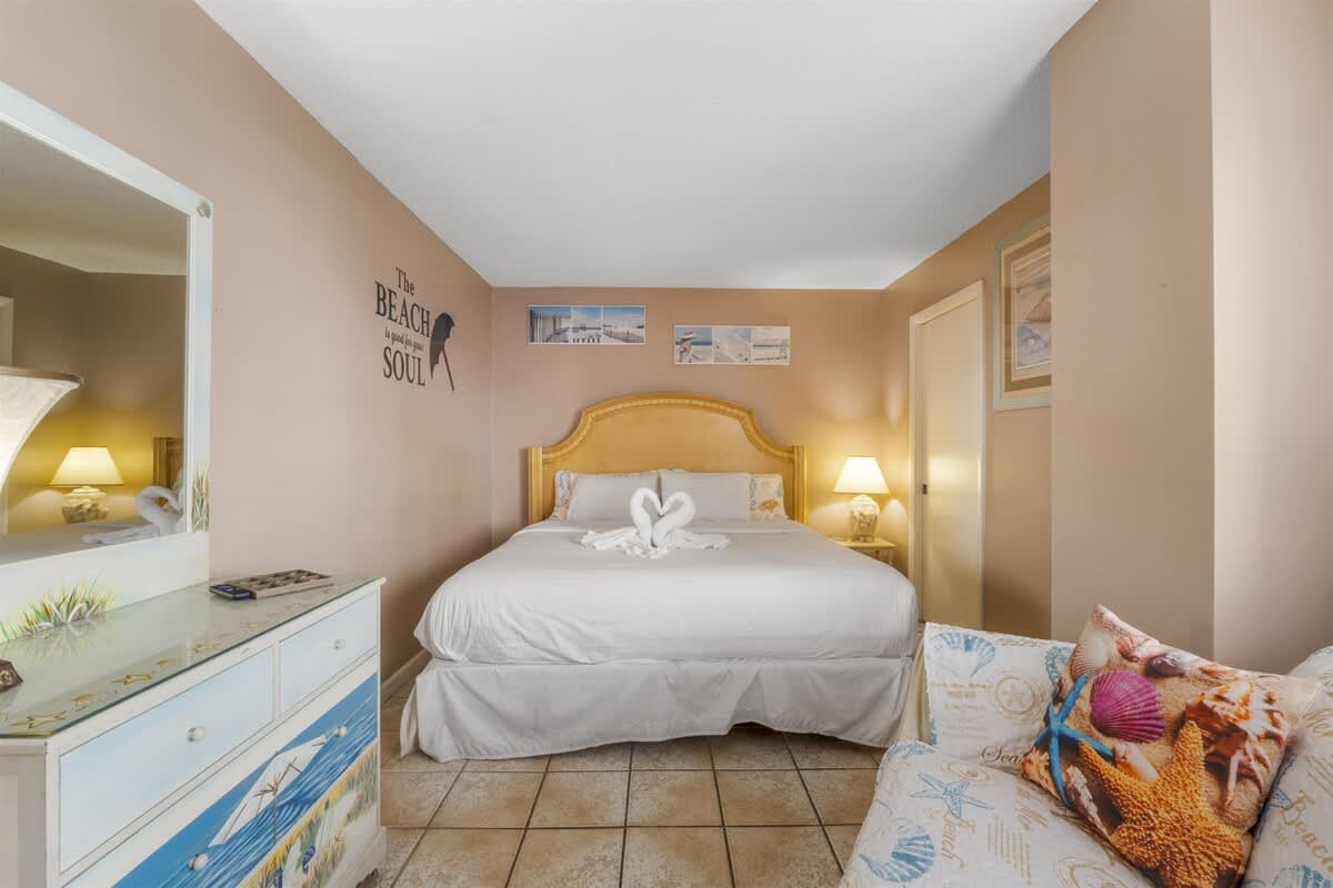 Moondrifter 207 – Cozy bedroom with a king bed, decorative pillows, nightstand, and dresser.