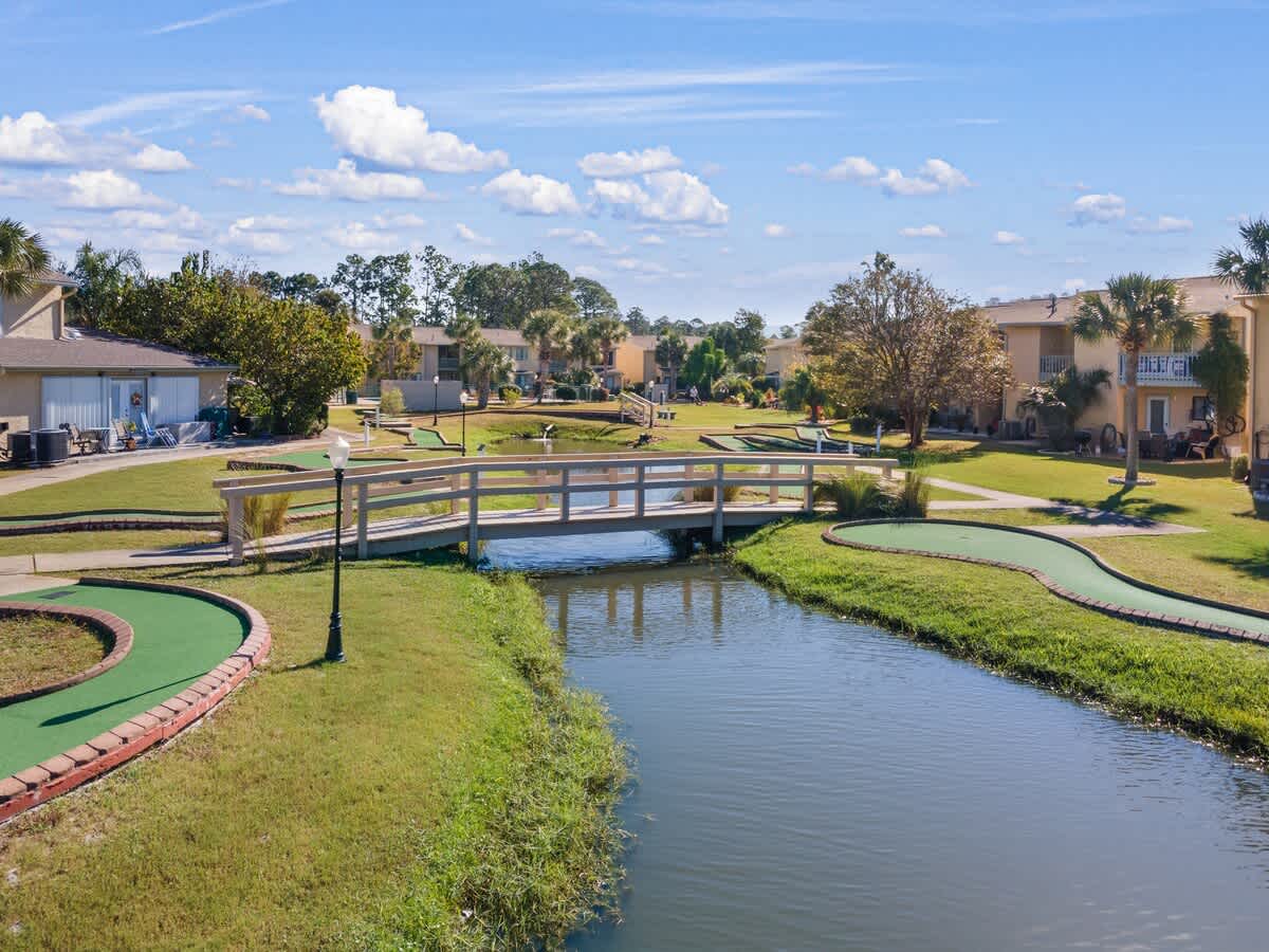 135 Grande Island Blvd – View of a green mini-golf course with a bridge over a canal and neighboring vacation rental buildings.