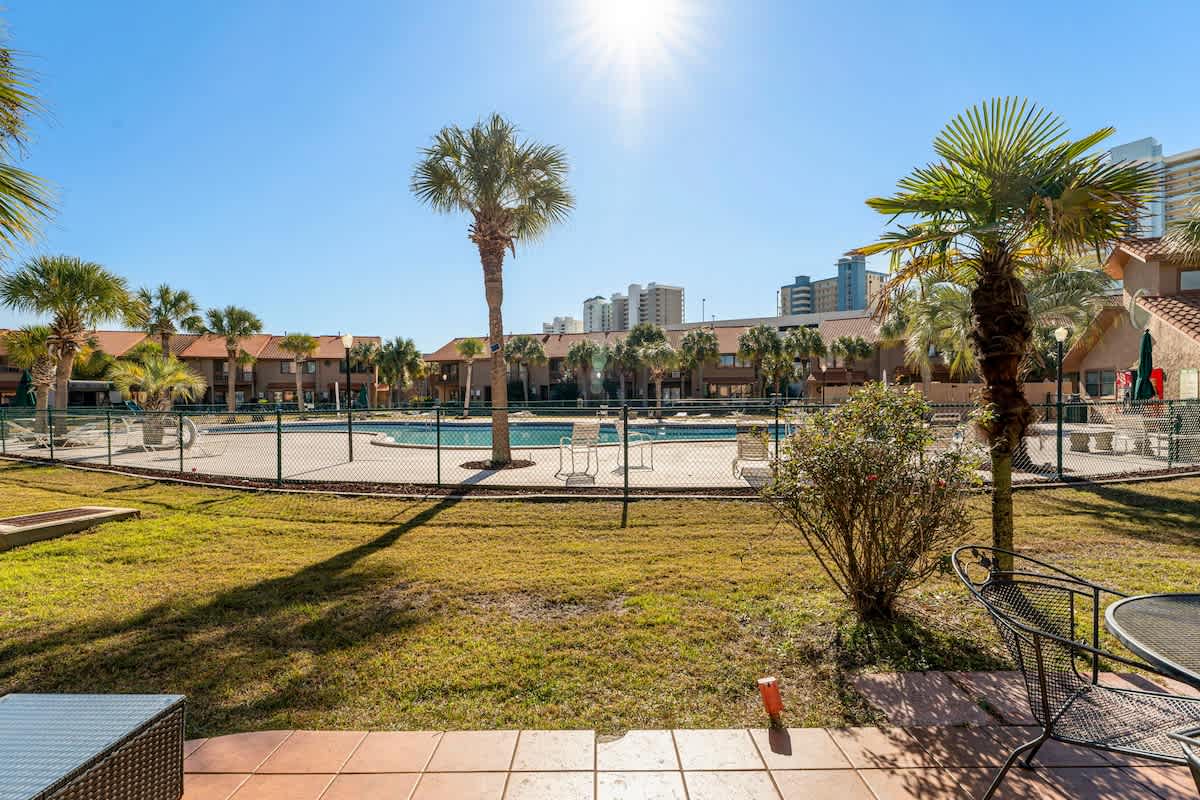 135 Grande Island Blvd – View of a pool area with palm trees and nearby buildings, sunny day.