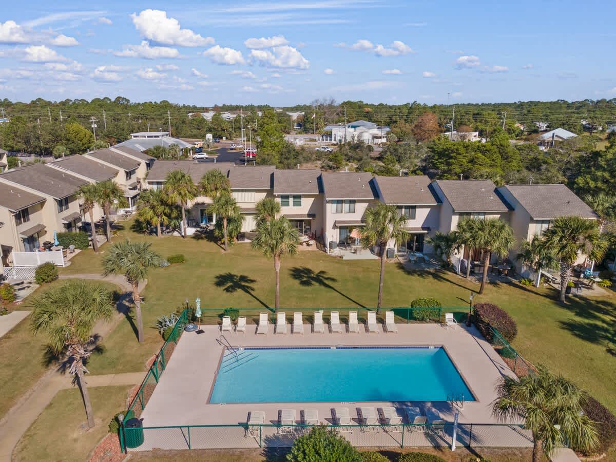 135 Grande Island Blvd – Aerial view of a pool surrounded by palm trees and vacation rental buildings.