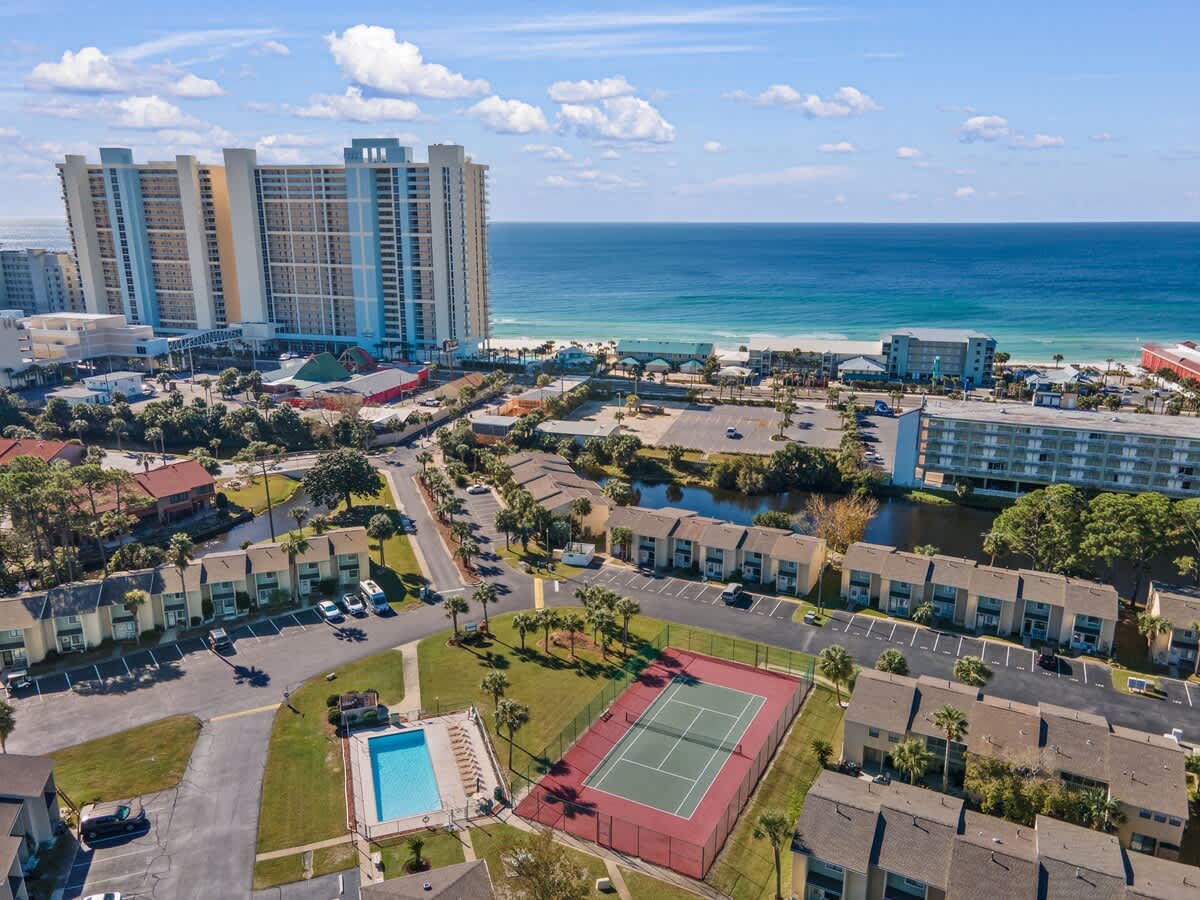 135 Grande Island Blvd – Aerial view of vacation rental complex with pool, tennis court, and ocean in the background.