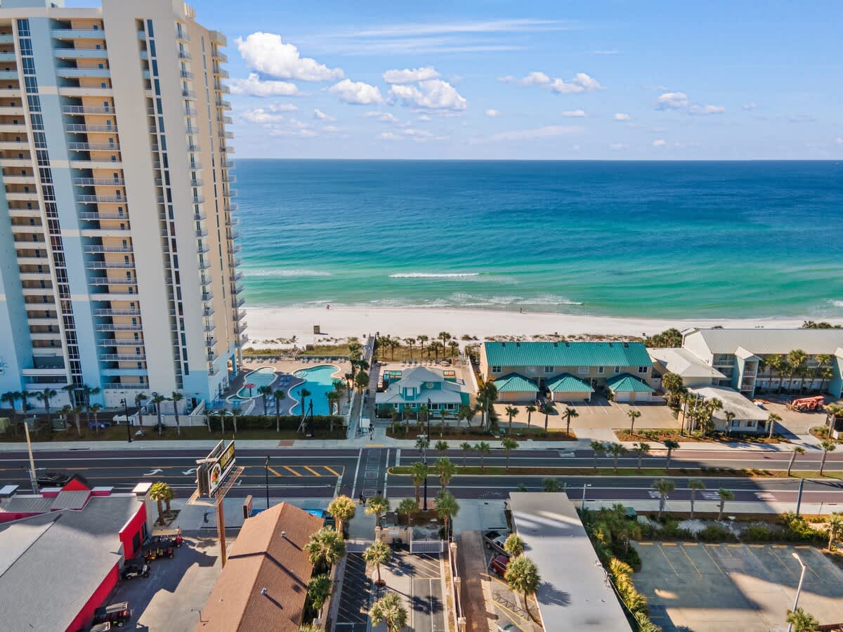 135 Grande Island Blvd – Tall beachfront building with pools, sandy beach, and clear blue ocean view.