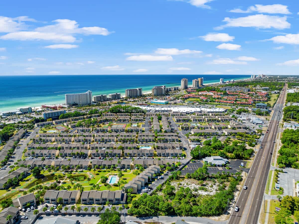 135 Grande Island Blvd – Aerial view of vacation rental community with ocean, high-rise buildings, and landscaped pool area.