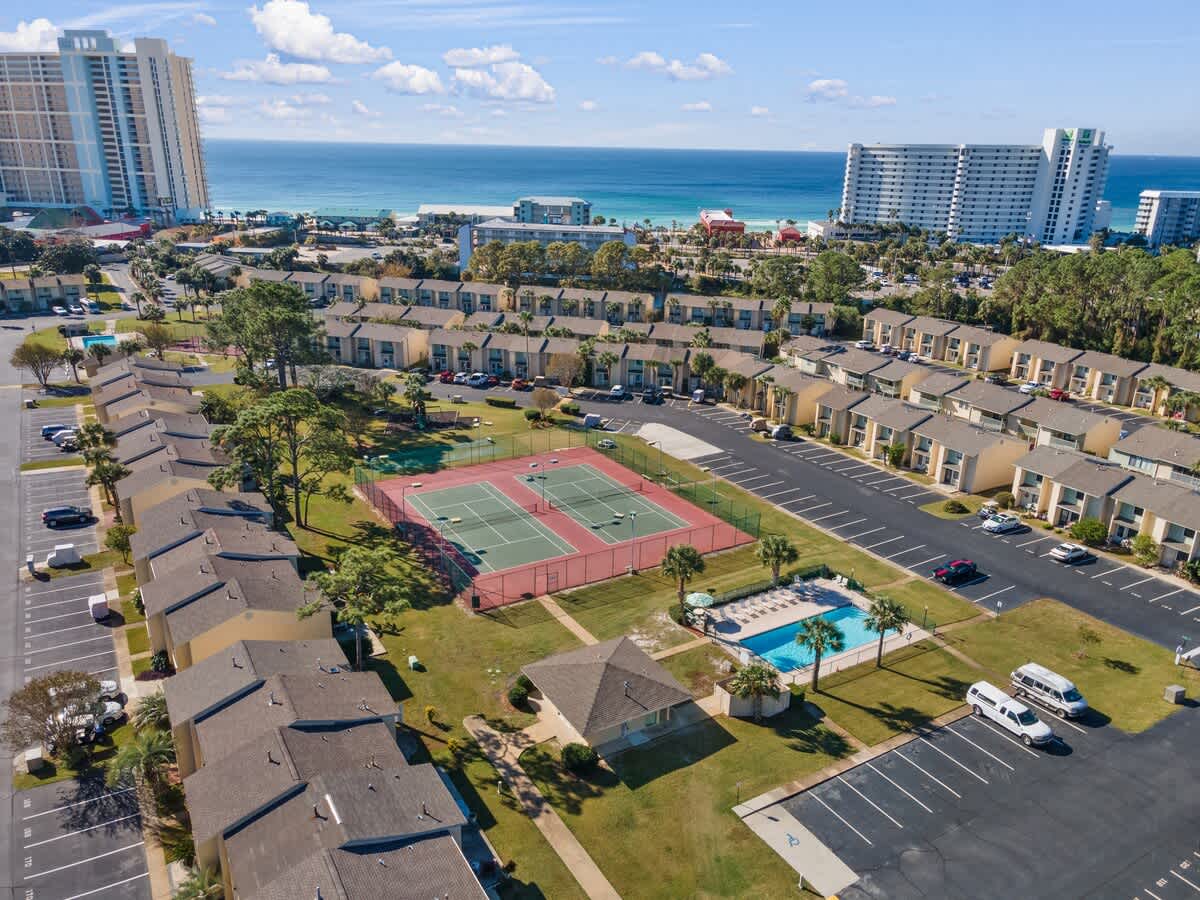 135 Grande Island Blvd – Aerial view of vacation rental complex, featuring tennis courts, swimming pool, and nearby beach with ocean view.