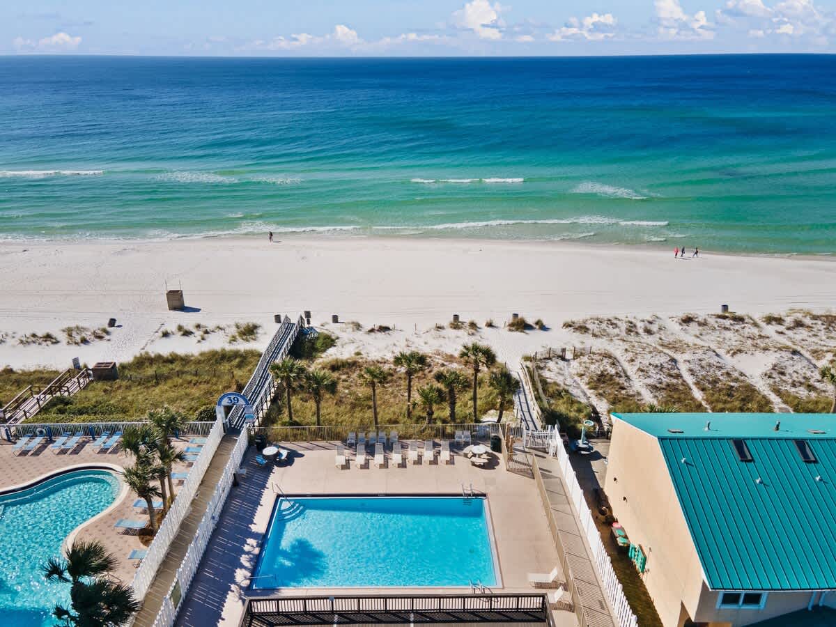 135 Grande Island Blvd – Aerial view of pools, beach, and ocean in a vacation rental setting.