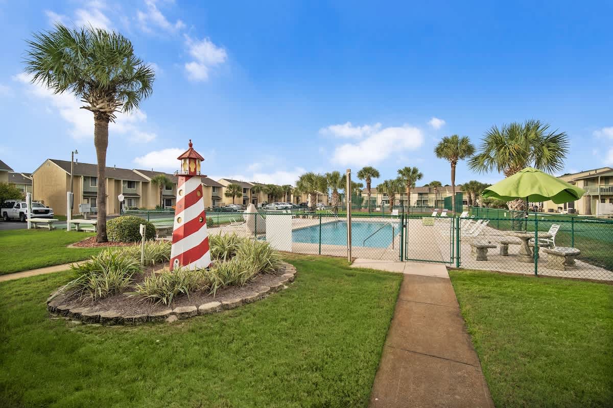 135 Grande Island Blvd – Pool area featuring a striped lighthouse, palm trees, and green umbrella seating.