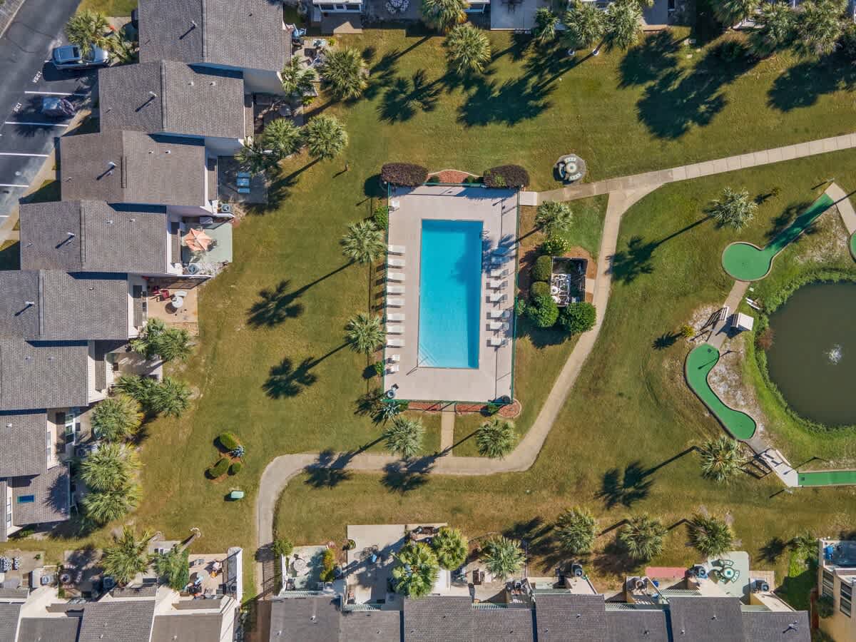 135 Grande Island Blvd – Aerial view of a pool surrounded by palm trees, lawns, and adjacent mini-golf course.