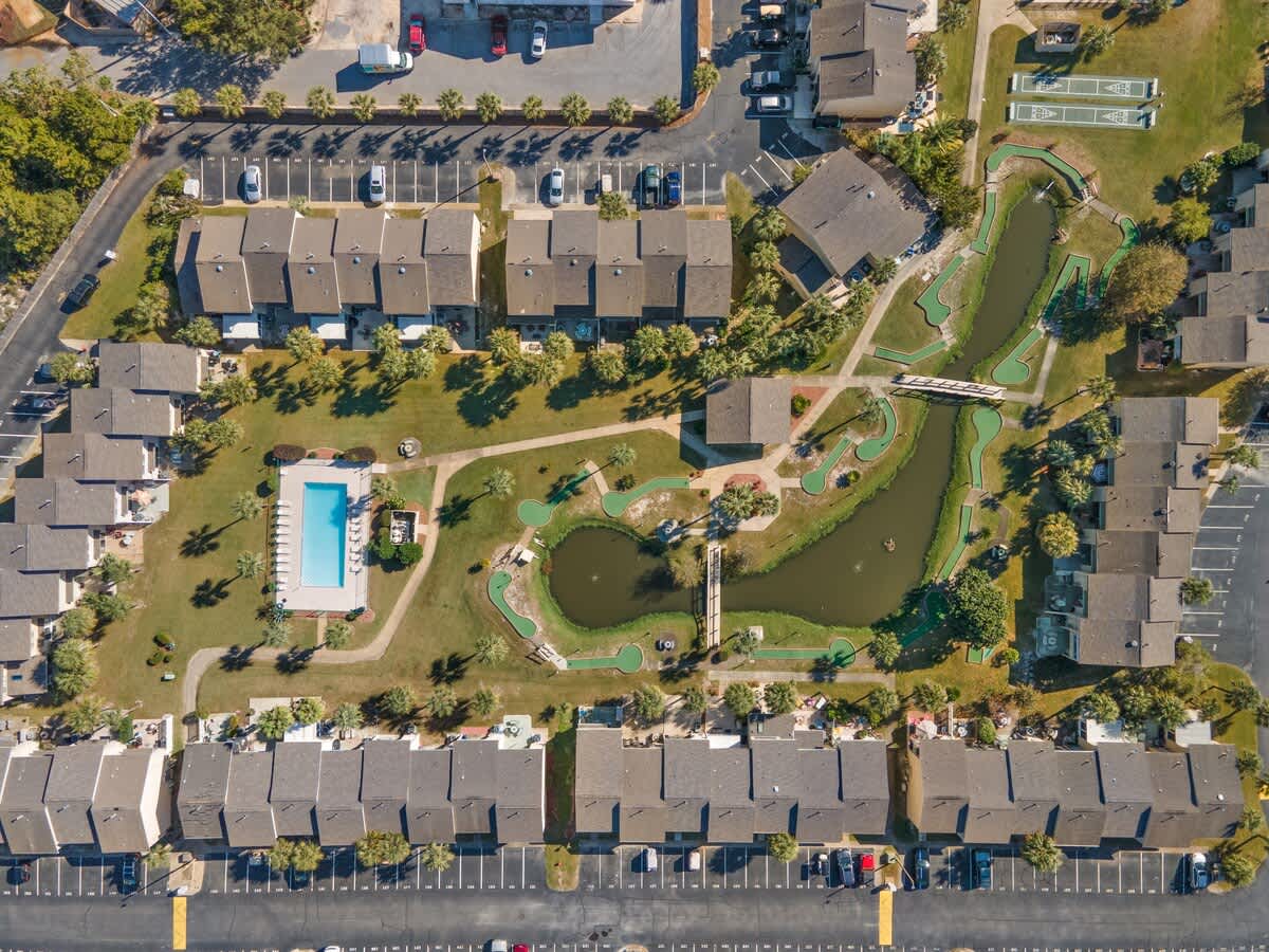 135 Grande Island Blvd – Aerial view of vacation rental complex featuring a pool, mini-golf, pond, and landscaped grounds.