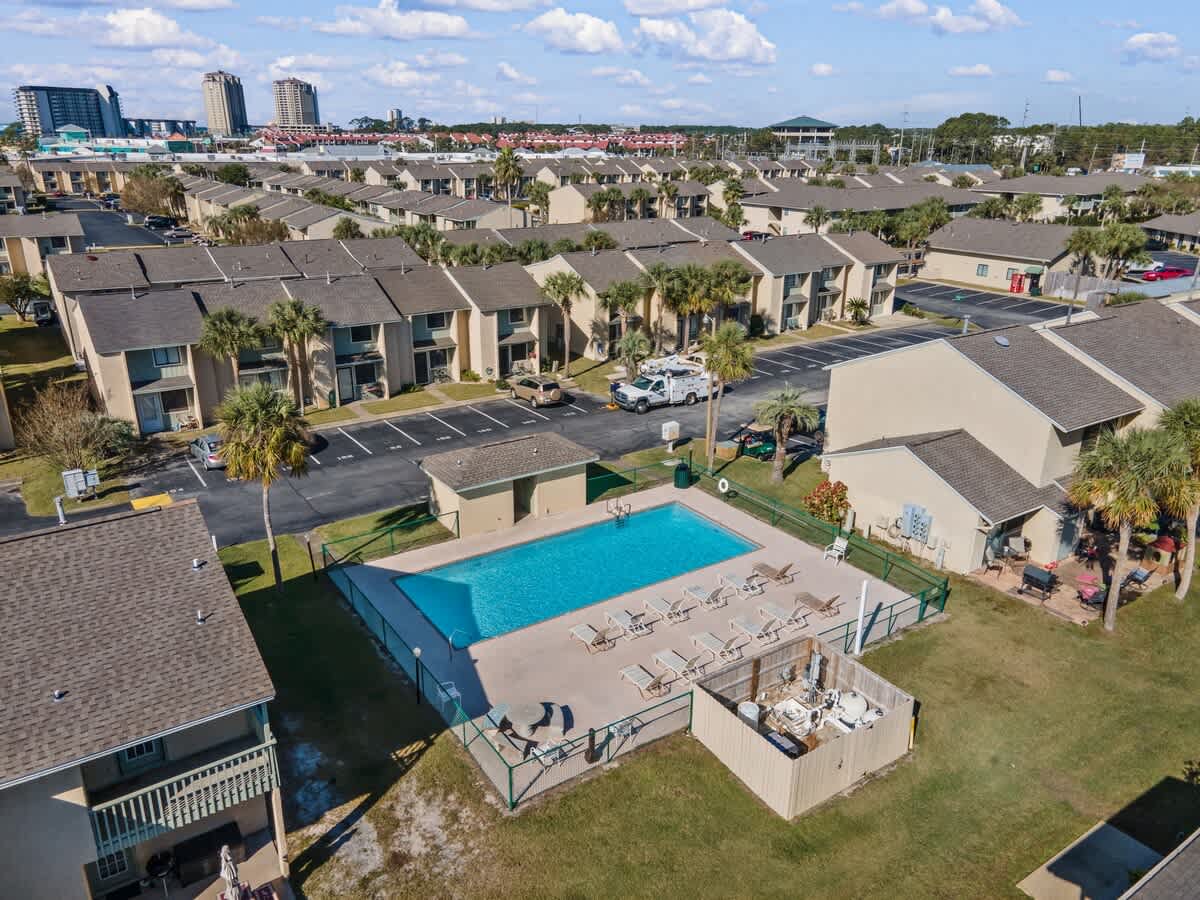 135 Grande Island Blvd – Aerial view of a swimming pool surrounded by palm trees and residential buildings.