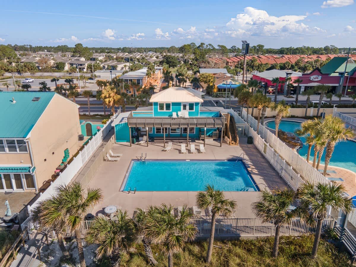 135 Grande Island Blvd – Aerial view of a pool area with lounge chairs, tropical landscaping, and adjacent buildings.