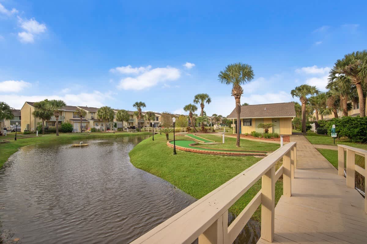 135 Grande Island Blvd – View of a landscaped area with a pond, walkways, and palm trees in a vacation rental complex.