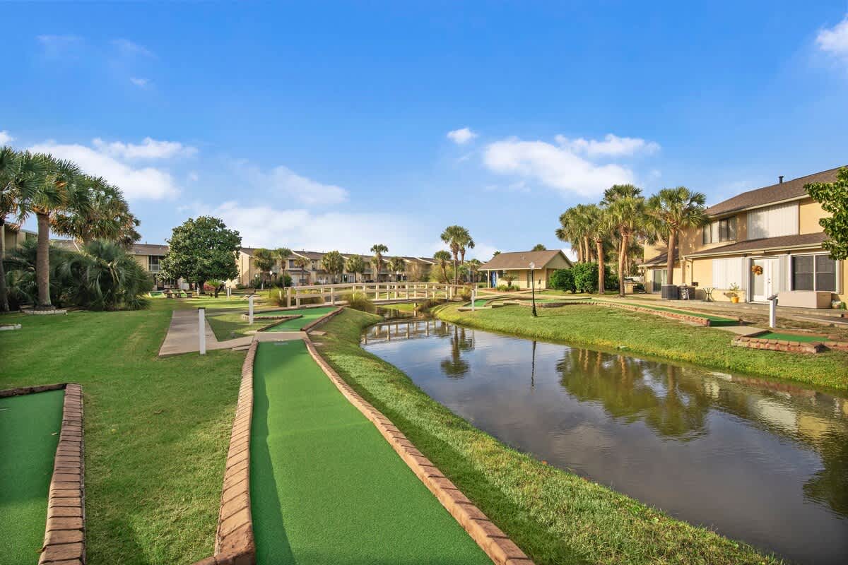 135 Grande Island Blvd – Mini golf course featuring green turf, a small pond, and residential buildings in the background.