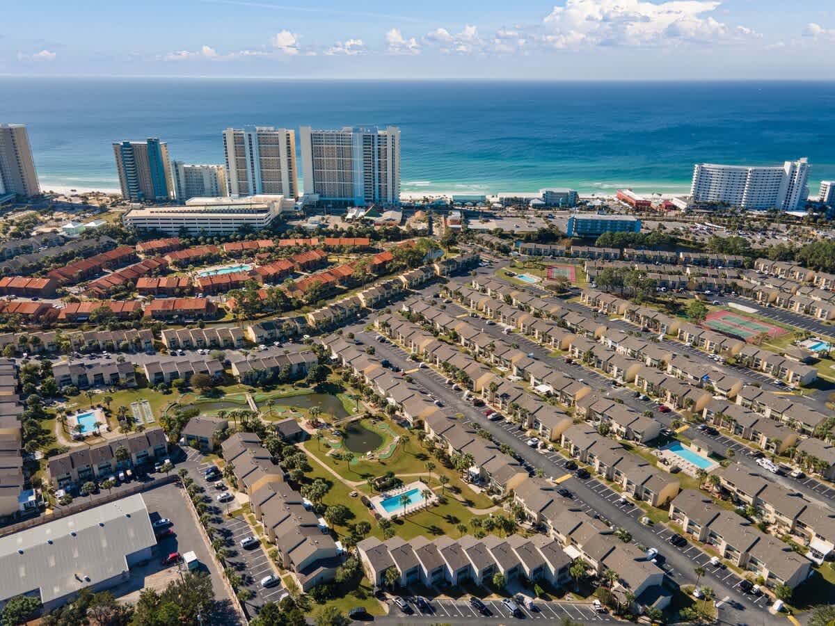 135 Grande Island Blvd – Aerial view of vacation rental complex with pools, tennis courts, and ocean in the background.