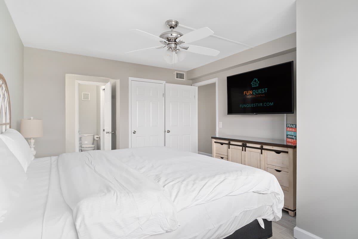 The Summit 529 – Spacious bedroom with a king bed, ceiling fan, TV, and adjoining bathroom.