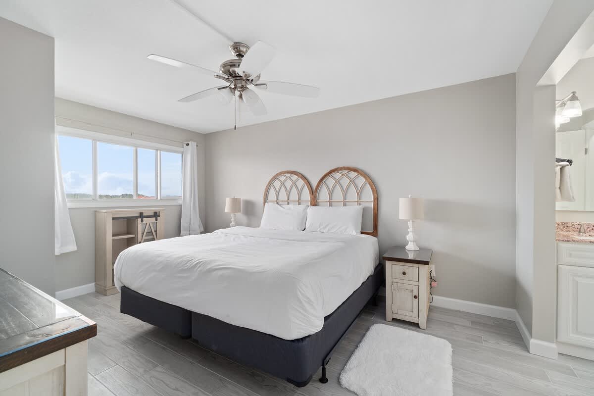 The Summit 529 – Bright bedroom with a queen bed, nightstand, and view outside through large window.