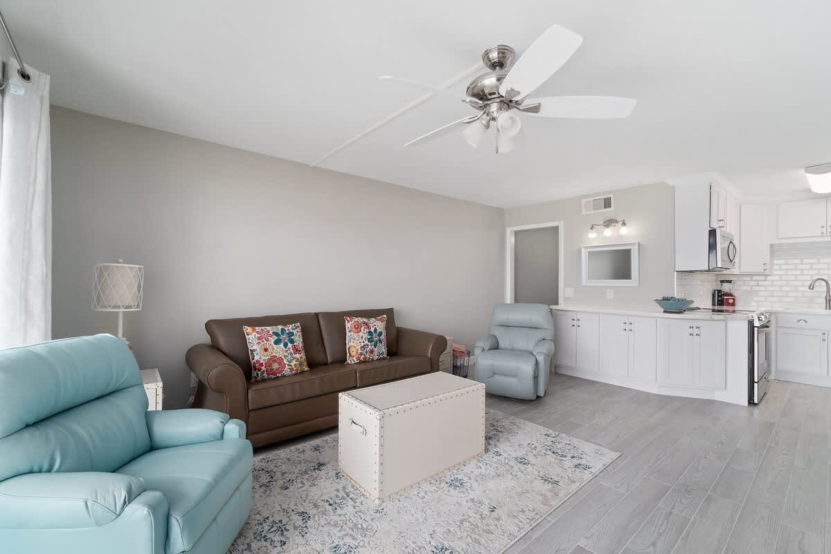 The Summit 529 – Living room with blue and brown seating, rug, coffee table, and adjacent kitchen area.
