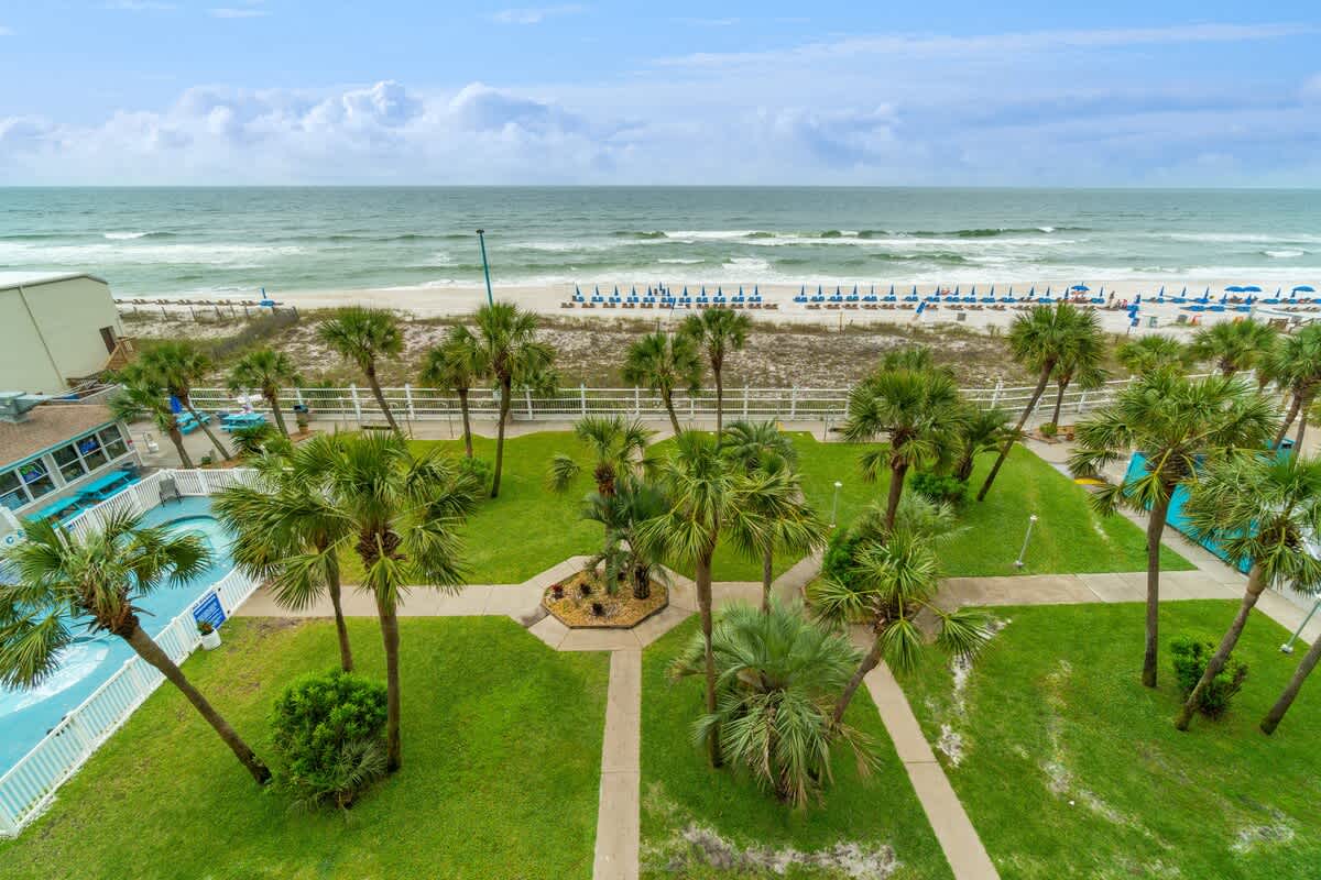 The Summit 529 – View of ocean, beach chairs, palm trees, and pool area from a higher vantage point.