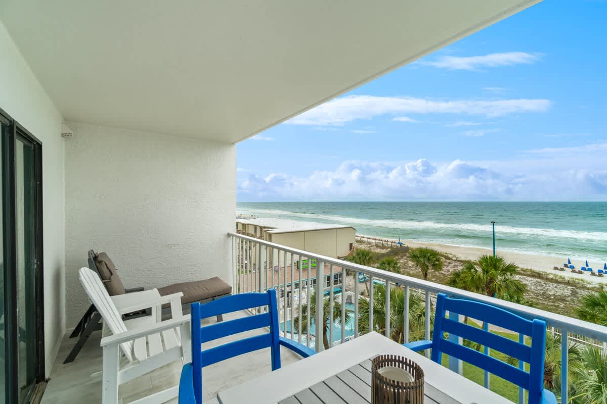 The Summit 529 – Balcony with ocean view, pool below, and beach chairs along the sandy shore.