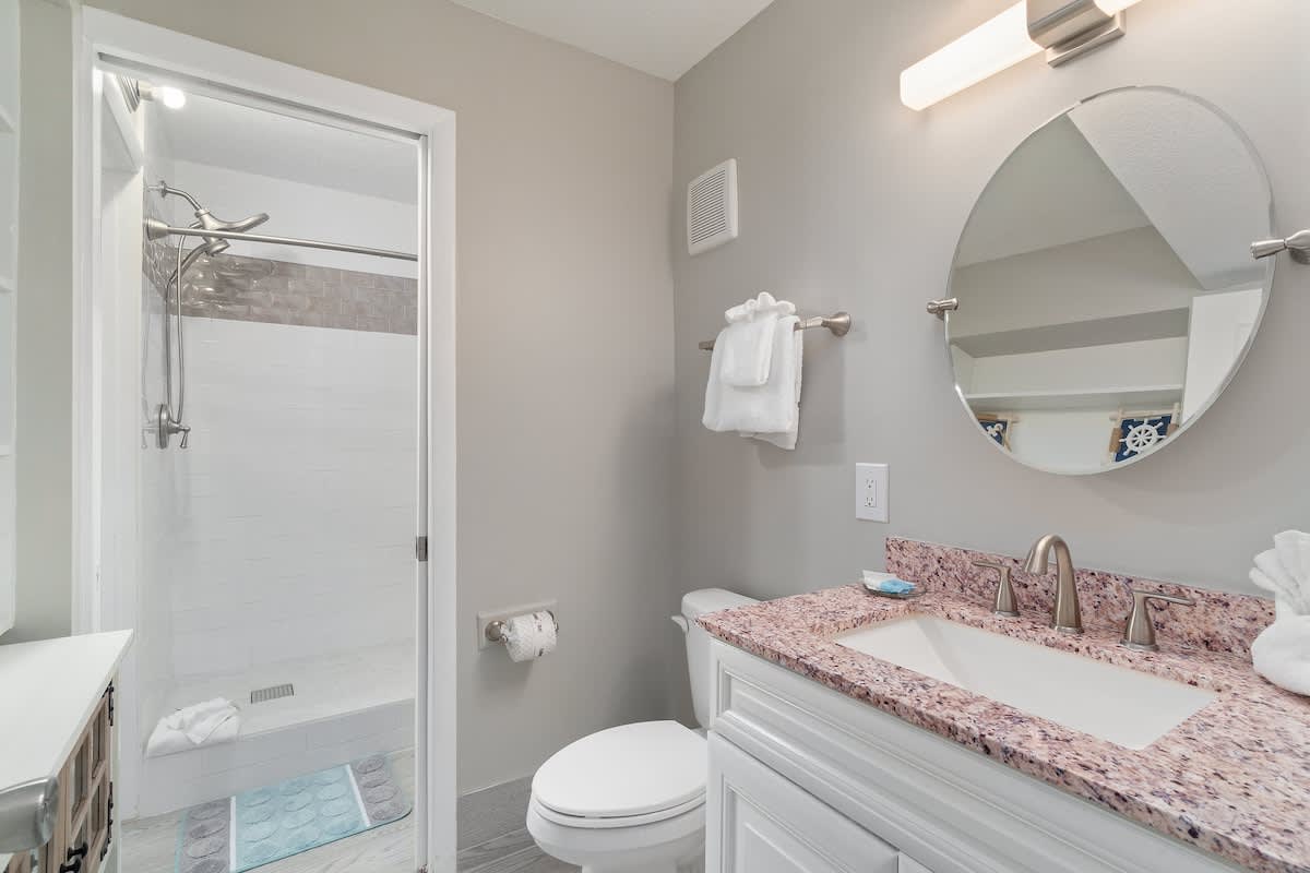 The Summit 529 – Bathroom with a walk-in shower, sink with pink granite countertop, and towels on racks.