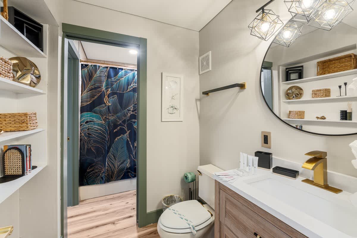 The Summit 1107 – Bathroom with modern fixtures, a round mirror, and a patterned shower curtain.