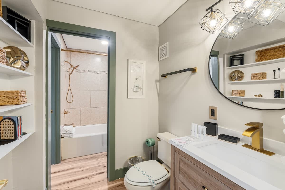 The Summit 1107 – Bathroom with modern fixtures, large mirror, and access to a tub/shower. Shelves with decorative items.