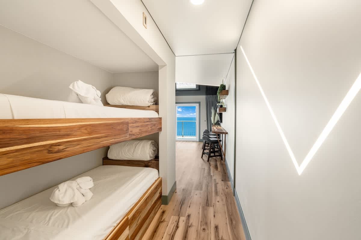 The Summit 1107 – Bunk beds in a hallway leading to a room with ocean view and wood flooring.