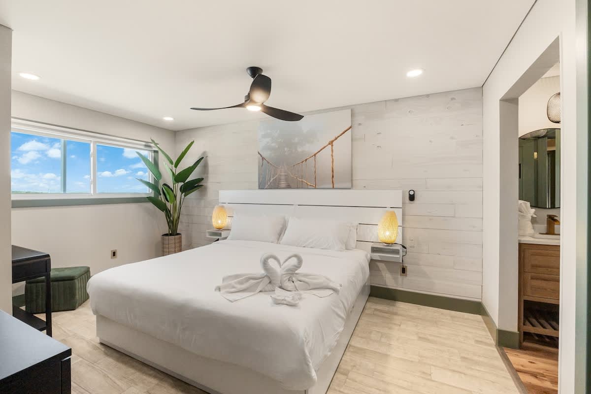 The Summit 1107 – Bright bedroom with a queen bed, two bedside lamps, and an en-suite bathroom visible.