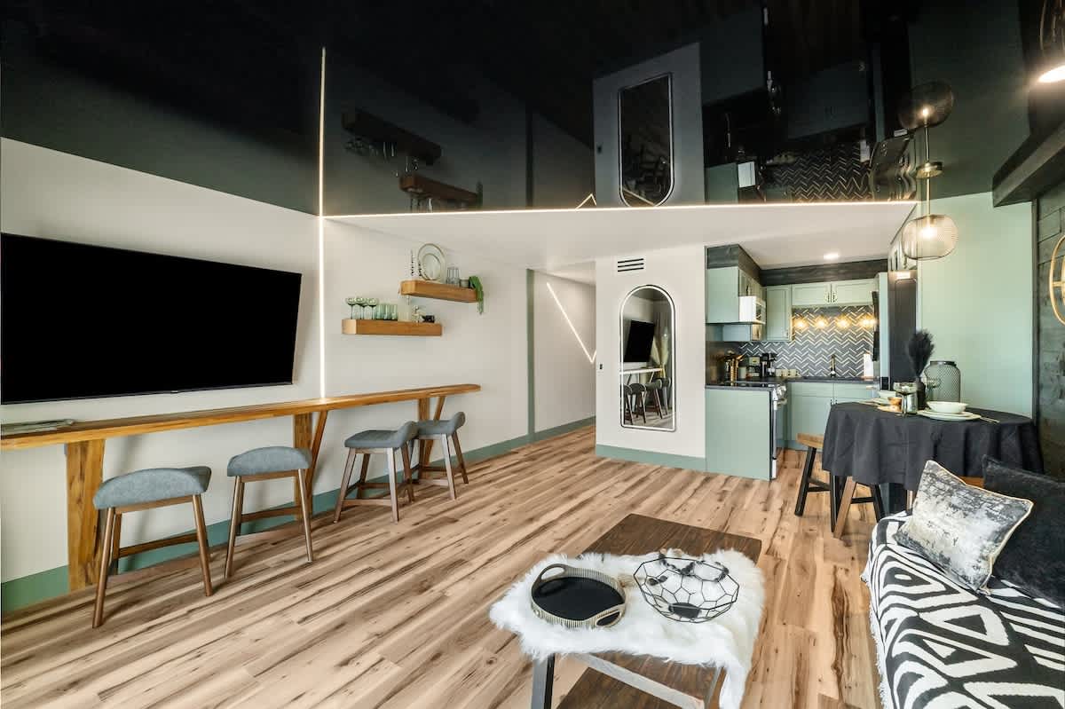 The Summit 1107 – Modern living area with a kitchen, bar stools, patterned sofa, and wooden flooring.