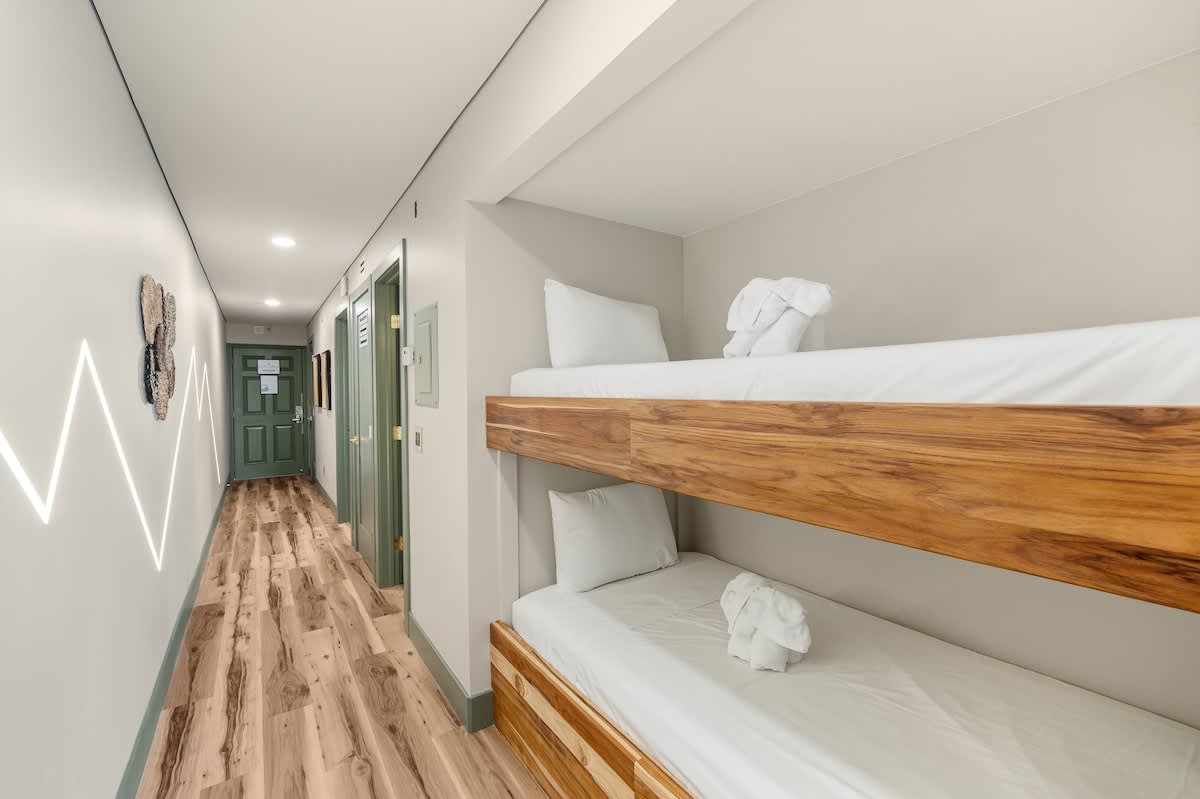 The Summit 1107 – Bunk beds in a hallway with light wood flooring and green doors.