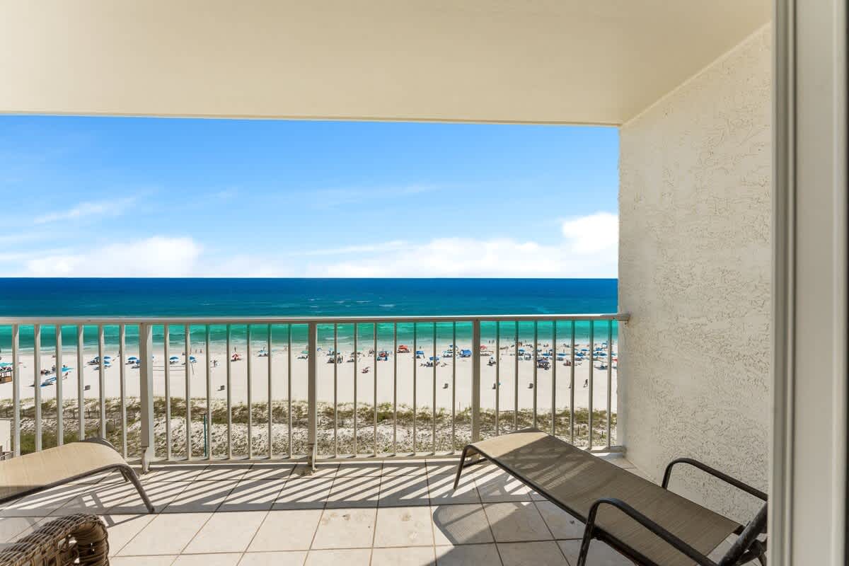 The Summit 927 – Oceanfront balcony view with beach chairs and a sandy beach below.