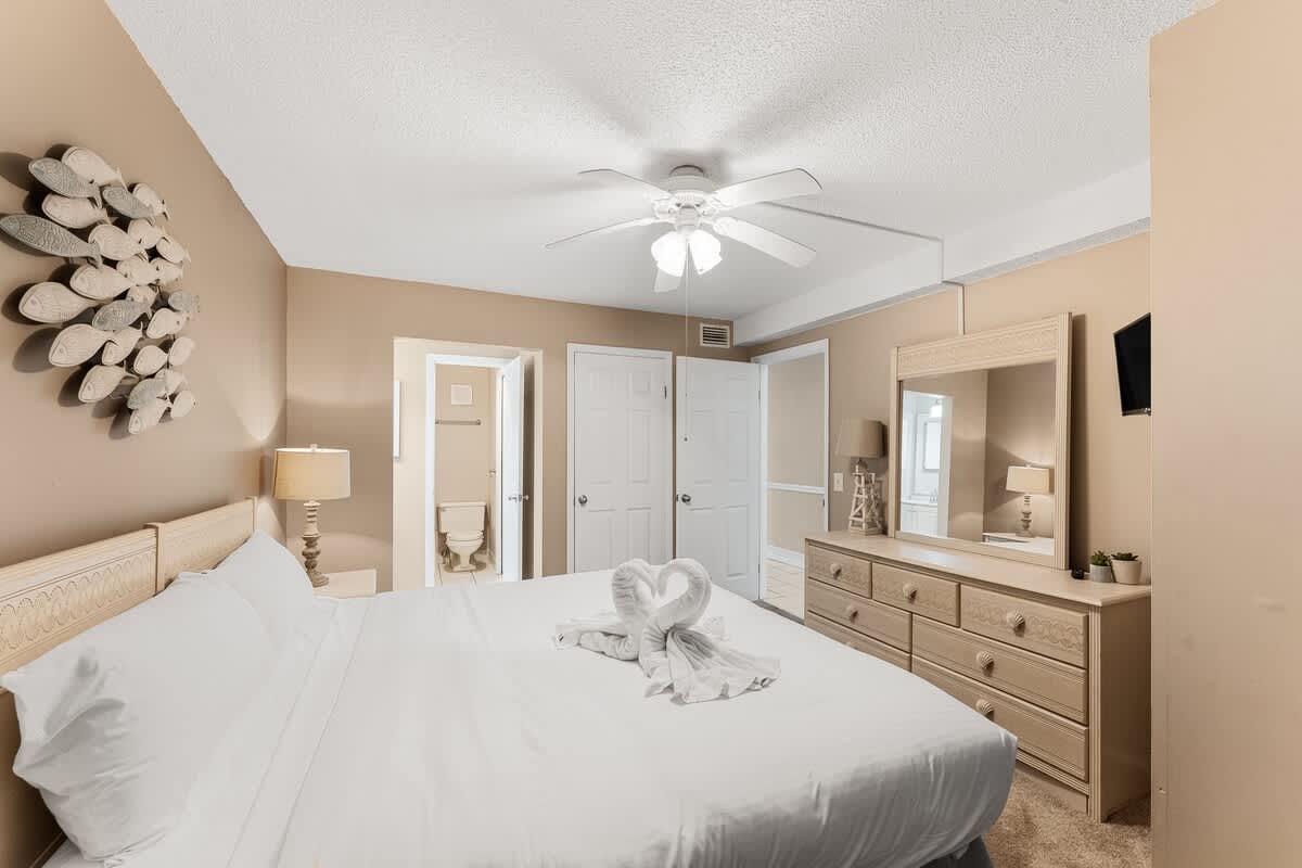 The Summit 927 – Cozy bedroom with a king bed, dresser, ceiling fan, and an en-suite bathroom.