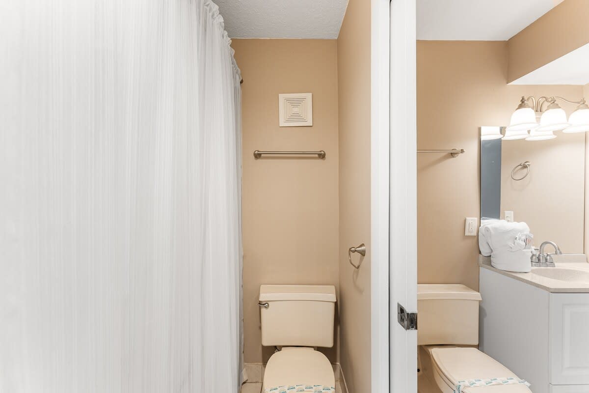 The Summit 927 – Bathroom with a shower curtain, toilet, sink, and beige walls.