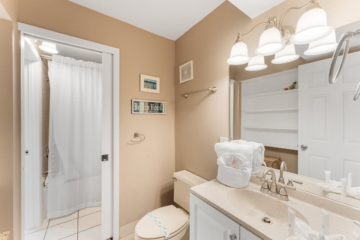 The Summit 927 – Bathroom with beige walls, shower curtain, sink, and toiletries on the counter.